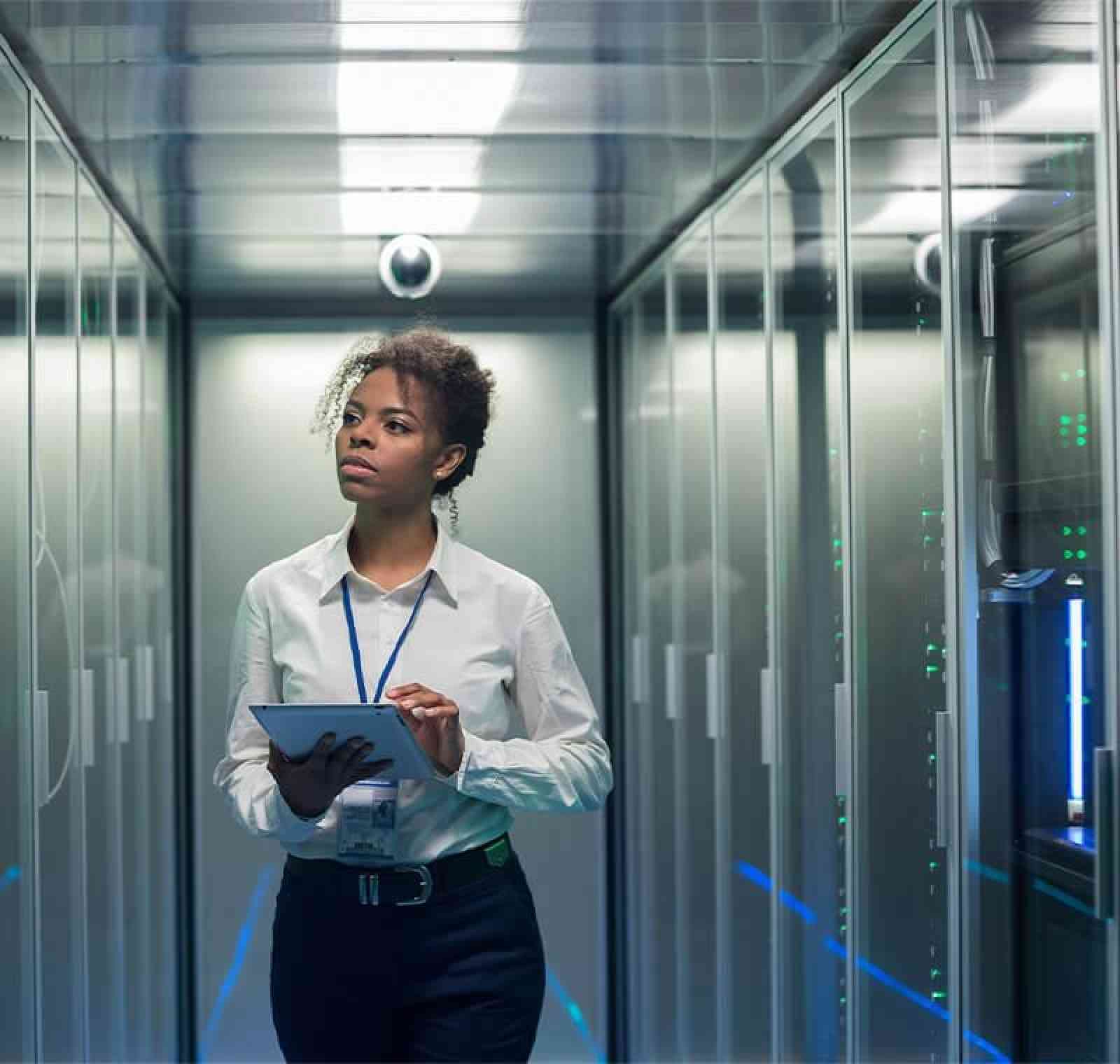 An IT network technician in a server room connects network cables and checks equipment, ensuring proper configuration and maintenance of computer systems and data connections.